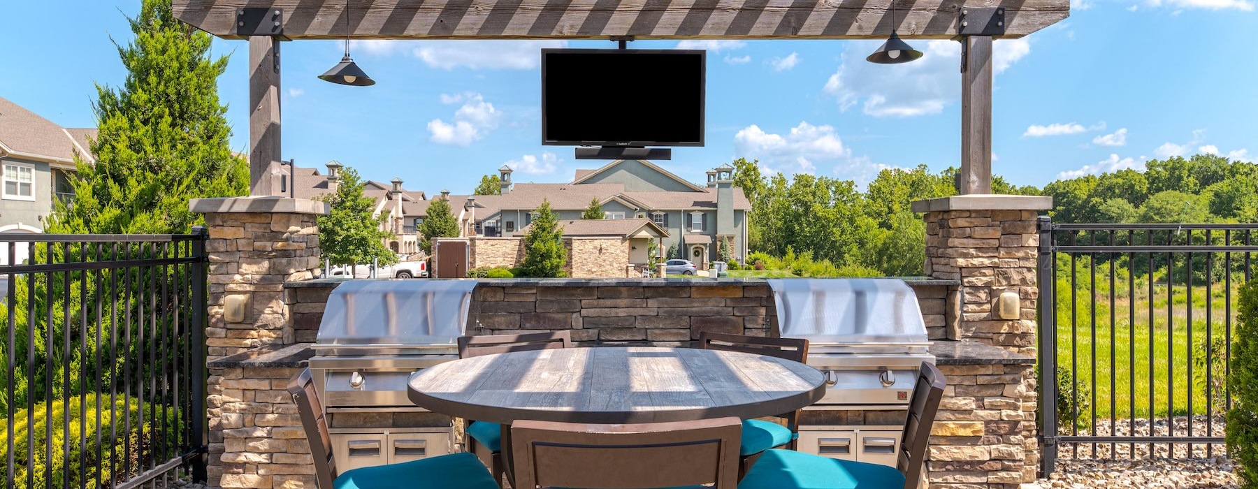 a grill area with a tv, table and chairs