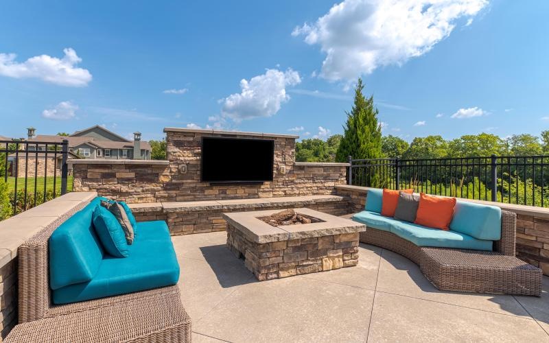 a patio with a fireplace, couches and a tv